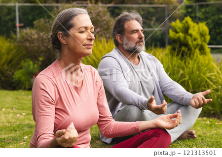 Meditating outdoors, mature couple finding peace in nature's serene setting 121313501