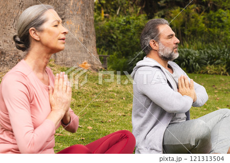 Meditating outdoors, mature couple focusing on relaxation and mindfulness together 121313504