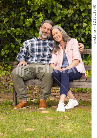 Happy mature couple sitting on park bench, enjoying peaceful moment together, outdoors Happy mature couple sitting on park bench, enjoying peaceful moment together, outdoors 121313540