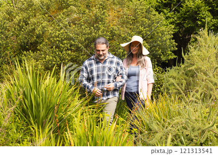 Mature couple walking through lush garden, enjoying peaceful nature together, outdoors 121313541