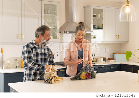 Mature couple unpacking groceries in modern kitchen, enjoying time together, at home Mature couple unpacking groceries in modern kitchen, enjoying time together, at home 121313545