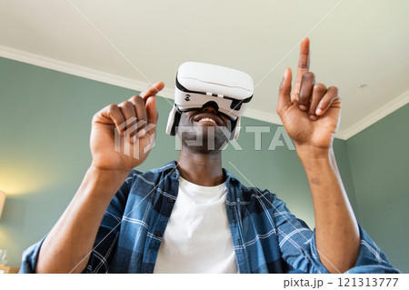 At home, African American man using virtual reality headset, smiling and interacting 121313777