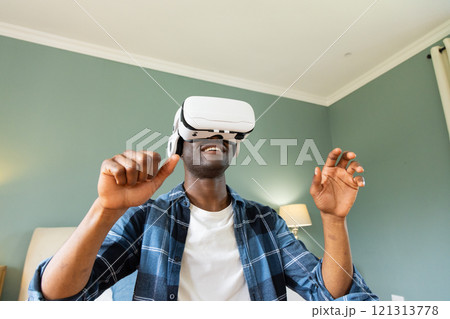 African American man enjoying virtual reality headset experience at home 121313778