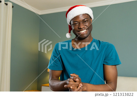 Christmas time, smiling african american man wearing santa hat at home Christmas time, smiling african american man wearing santa hat at home 121313822