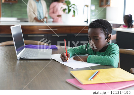 African american boy having online class using headphones and laptop with copy space, slow motion 121314196