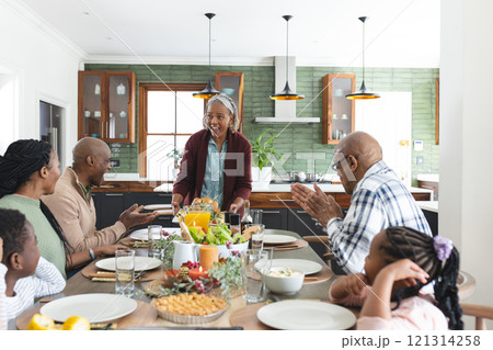 Happy african american multi generation family serving food at thanksgiving dinner 121314258