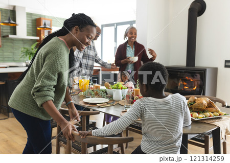 Happy african american multi generation family serving food at thanksgiving dinner 121314259