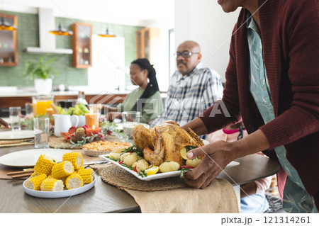 Happy african american multi generation family serving food at thanksgiving dinner 121314261