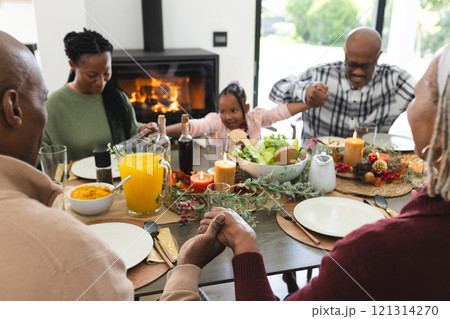 Happy african american multi generation family holding hands at thanksgiving dinner 121314270