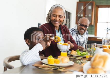 Happy african american grandmother serving food for grandson at thanksgiving dinner 121314276