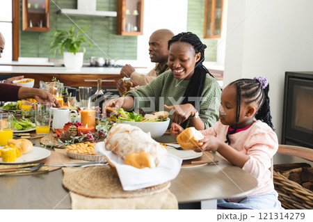 Happy african american mother serving food for daughter at thanksgiving dinner 121314279