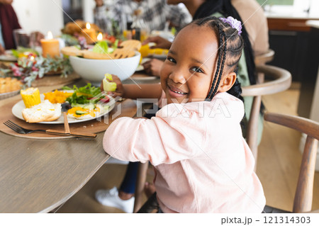 Portrait of african american daughter smiling at thanksgiving dinner table Portrait of african american daughter smiling at thanksgiving dinner table 121314303