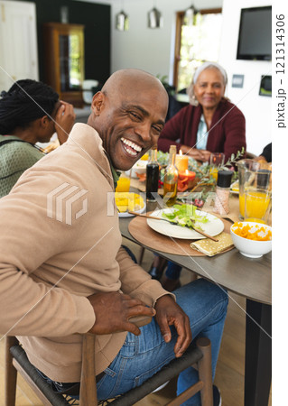 Portrait of african american father with family laughing at thanksgiving dinner table 121314306