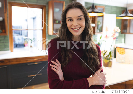 Portrait of happy caucasian woman wearing red jumper smiling in kitchen at home 121314504