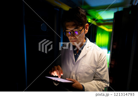 Asian male engineer wearing an apron using digital tablet in computer server room Asian male engineer wearing an apron using digital tablet in computer server room 121314793