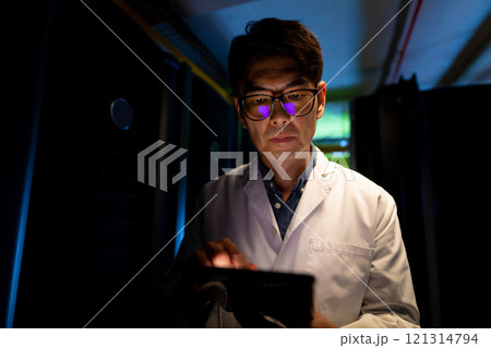 Asian male engineer wearing an apron using digital tablet in computer server room 121314794
