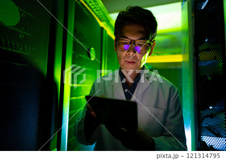 Asian male engineer wearing an apron using digital tablet in computer server room 121314795