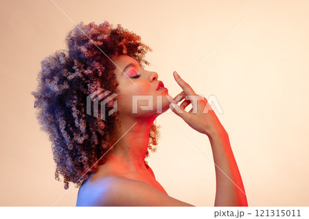 Biracial woman wearing pink eyeshadow and lipstick with eyes closed in red and blue light Biracial woman wearing pink eyeshadow and lipstick with eyes closed in red and blue light 121315011