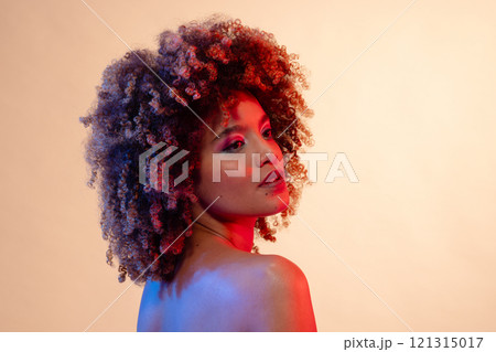 Biracial woman with curly hair, pink eyeshadow, red and blue light, copy space 121315017