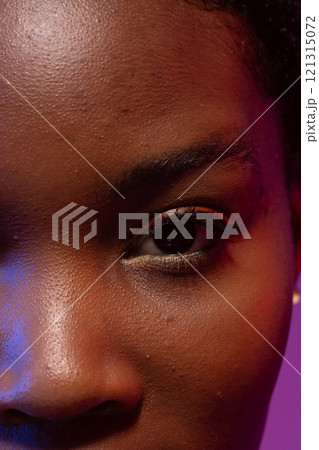Close up of eye and nose of african american woman on purple background Close up of eye and nose of african american woman on purple background 121315072