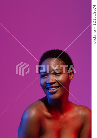 African american woman looking away smiling, in blue and red light on purple background, copy space African american woman looking away smiling, in blue and red light on purple background, copy space 121315074