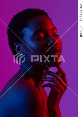 African american woman touching chin with eyes closed in red light on purple background African american woman touching chin with eyes closed in red light on purple background 121315102