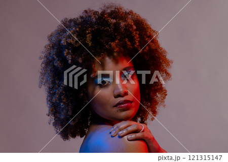 Biracial woman with curly hair and hand on shoulder in blue and red light Biracial woman with curly hair and hand on shoulder in blue and red light 121315147