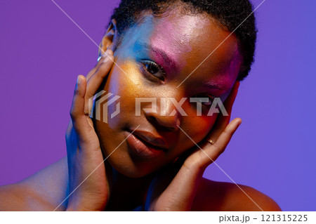 African american woman with short hair and colourful make up touching face 121315225