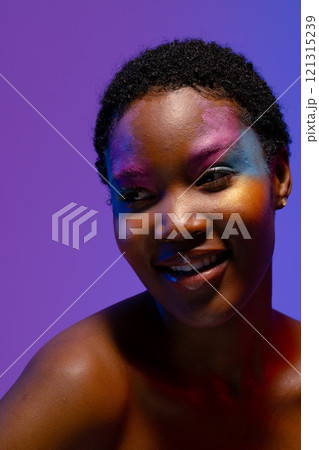 Smiling african american woman with short hair and colourful makeup looking away 121315239