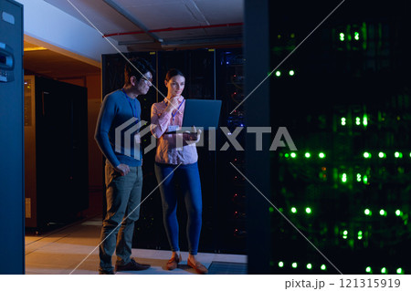 Diverse male and female engineers using laptop in computer server room 121315919