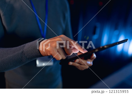 Mid section of male engineer using digital tablet in computer server room 121315955