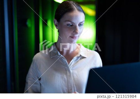 Caucasian female engineer using laptop in computer server room 121315984