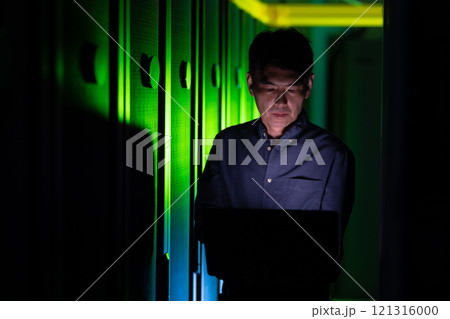 Asian male engineer using laptop in computer server room Asian male engineer using laptop in computer server room 121316000