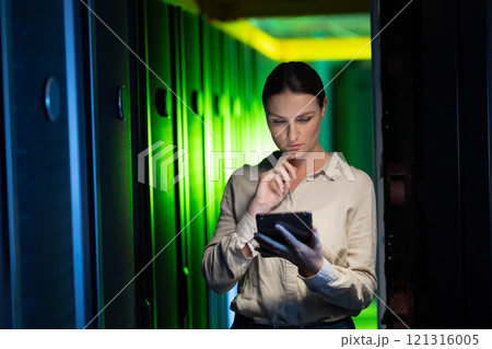 Thoughtful caucasian female engineer using digital tablet in computer server room 121316005