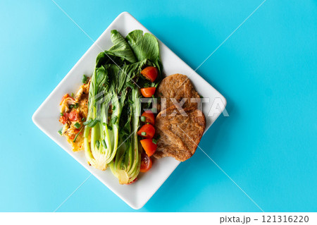 A vibrant dish features bok choi, vegetarian meat patties, and fresh diced tomatoes. A vibrant dish features bok choi, vegetarian meat patties, and fresh diced tomatoes. 121316220
