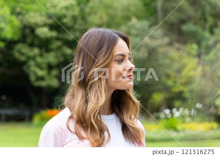Smiling woman enjoying peaceful moment in lush green park setting Smiling woman enjoying peaceful moment in lush green park setting 121316275
