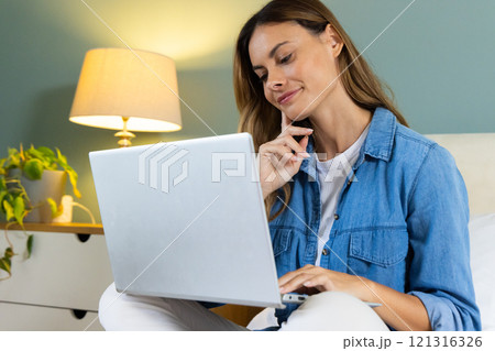 At home, woman using laptop and smiling, feeling relaxed and content 121316326