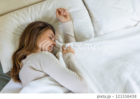 Woman peacefully sleeping in cozy bed, enjoying restful night at home 121316438