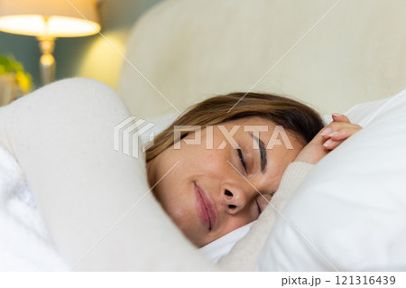Woman peacefully sleeping in cozy bed, enjoying restful night at home 121316439