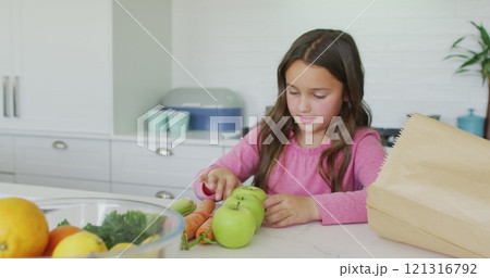 Happy caucasian girl unpacking groceries in kitchen 121316792