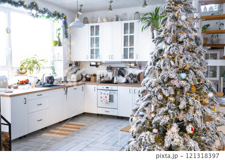 Christmas decor in white kitchen, modern rustic interior with a snowy Christmas tree and gold fairy lights. New Year, Christmas mood, cozy home. Christmas decor in white kitchen, modern rustic interior with a snowy Christmas tree and gold fairy lights. New Year, Christmas mood, cozy home. 121318397