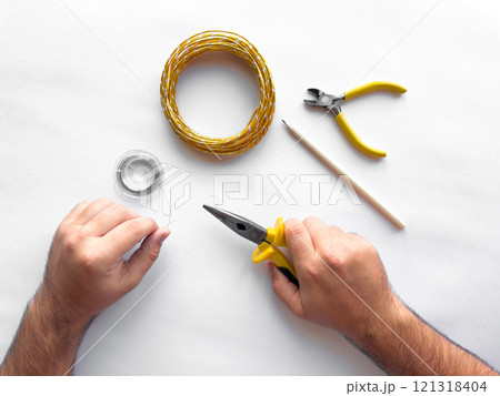 Hands crafting wire jewelry with tools on white background Hands crafting wire jewelry with tools on white background 121318404