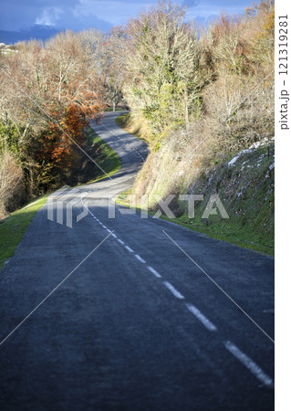 Winding rural road through forest in autumn with cloudy sky Winding rural road through forest in autumn with cloudy sky 121319281