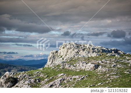 Rocky landscape with grassy foreground and dramatic cloudy sky Rocky landscape with grassy foreground and dramatic cloudy sky 121319282