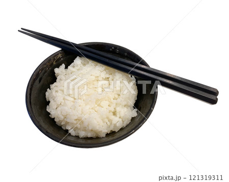 A black ceramic bowl filled with steamed white rice, accompanied by a pair of black chopsticks resting on the rim, set against a white background. A black ceramic bowl filled with steamed white rice, accompanied by a pair of black chopsticks resting on the rim, set against a white background. 121319311