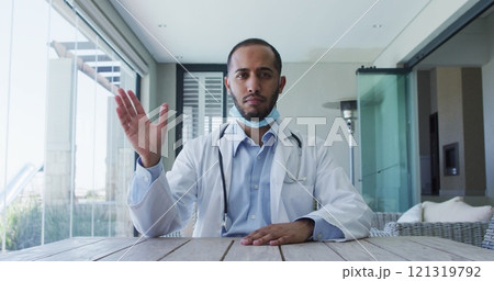 Biracial male doctor wearing face mask talking during image call 121319792