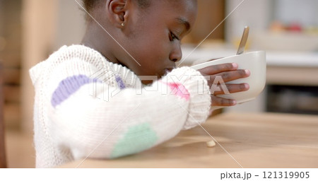 African american girl eating cereal with milk in kitchen African american girl eating cereal with milk in kitchen 121319905
