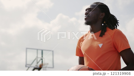 Low angle view of African american basketball player standing with basketball in court 121319908