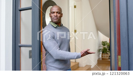 Happy african american man welcoming at his front door Happy african american man welcoming at his front door 121320063
