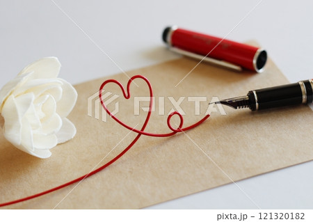 白いソラフラワーと茶色のメッセージカード　赤い万年筆で書くイメージ　赤いハートのワイヤー 121320182